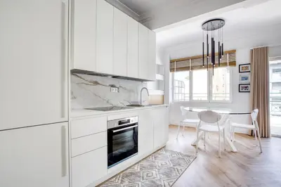 a kitchen with white cabinets and a table with chairs at Whitewood Residence in Athens
