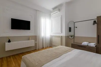a white bedroom with a bed and a flat screen tv at Timeless Plaka Retreat in Athens