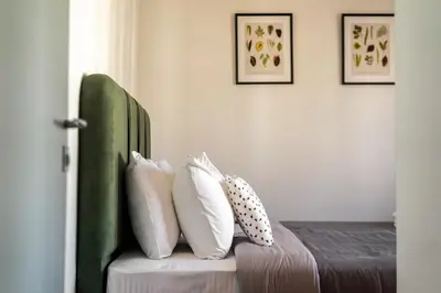 a bed with white pillows and a green headboard at Sunny 3bd flat,Acropolis view in Athens