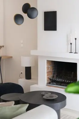 a living room with a fireplace and a table and chairs at Comfort Seaside 2BR Apartment in Palaio Faliro by UPSTREET in Athens