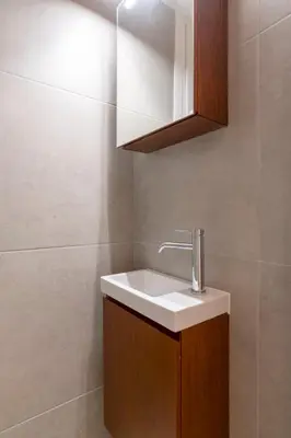 a bathroom with a white sink and a cabinet at Comfort Seaside 2BR Apartment in Palaio Faliro by UPSTREET in Athens