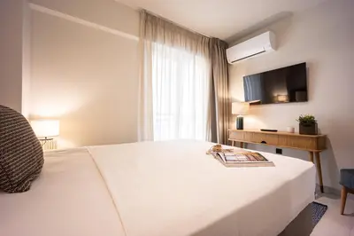 a hotel room with a white bed and a television at Marbella Living Pangrati By O&O Group in Athens