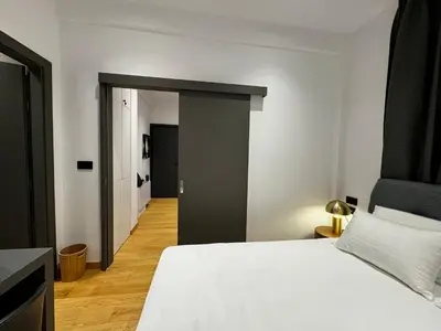 a bedroom with a white bed and a hallway at Downtown Modern Suite in Athens