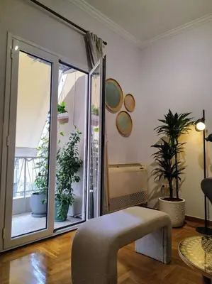 a living room with a large sliding glass door with potted plants at Spacious modern flat in Koukaki in Athens
