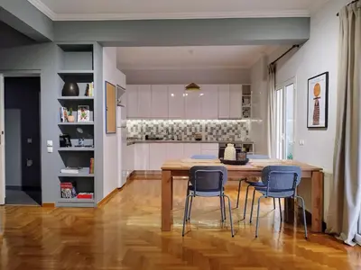 a kitchen and dining room with a wooden table and chairs at Spacious modern flat in Koukaki in Athens