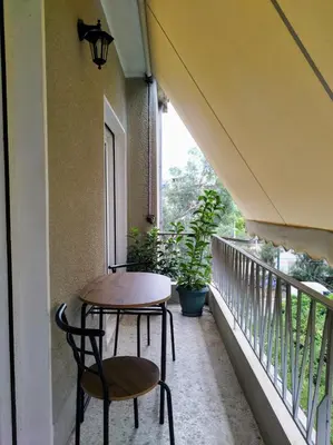 a table and chairs on a balcony with a window at Spacious modern flat in Koukaki in Athens