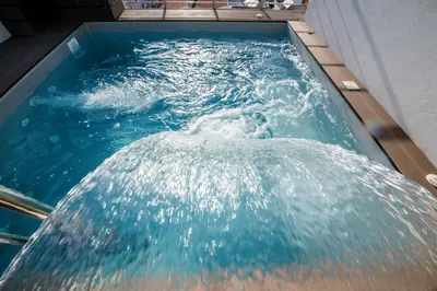 a pool of blue water with a waterfall at Nikki's Skylight Suite in Athens