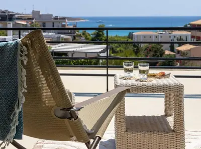 a table and chairs on a balcony with glasses of wine at 2BD Luxury Sea View Penthouse in Astir Beach in Athens