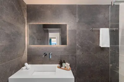 a bathroom with a sink and a shower with a mirror at 2BD Luxury Sea View Penthouse in Astir Beach in Athens