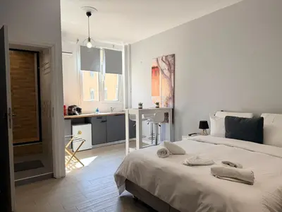 a white bedroom with a bed and a kitchen at Aiolou 68str rooms & apartments in Athens