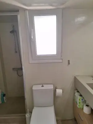 a bathroom with a toilet with a window above it at Cozy renovated flat with balcony in Athens