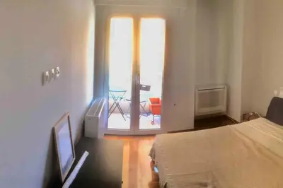 a bedroom with a bed and a window with a chair at Cozy renovated flat with balcony in Athens