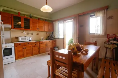 a kitchen with wooden cabinets and a wooden table at Marousa's Country House 12 minutes from Athens Airport in Koropíon