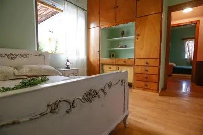 a bedroom with a white bed and a wooden floor at Marousa's Country House 12 minutes from Athens Airport in Koropíon