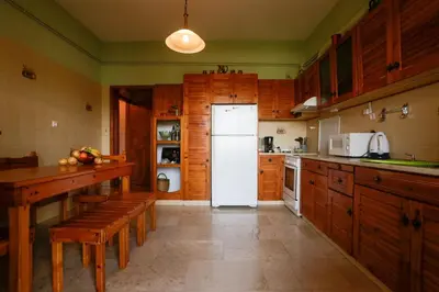 a kitchen with a white refrigerator and wooden cabinets at Marousa's Country House 12 minutes from Athens Airport in Koropíon