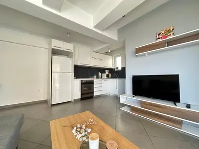 a living room with a large television and a kitchen at 6th Floor Serenity Apartment in Zografou, Athens in Athens