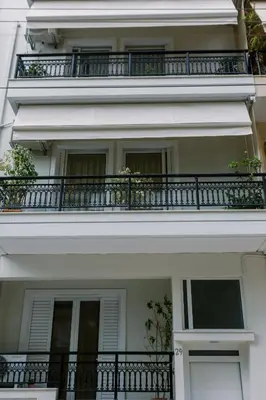 a white building with a balcony with plants on it at Cozy 2 Bedroom Apartment Gaia by Philoxenia in Athens