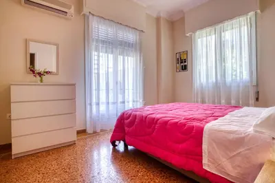 a bedroom with a pink bed and a dresser and windows at Acropolis Vintage Apartment in Athens