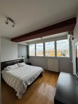 a bedroom with a large bed and large windows at Sunlit Panorama Faliro in Athens