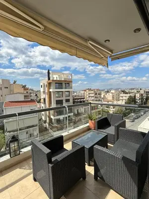 a balcony with chairs and tables and a view of a city at Sunlit Panorama Faliro in Athens
