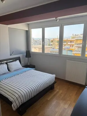 a bedroom with a bed and two large windows at Sunlit Panorama Faliro in Athens