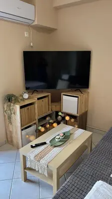 a living room with a table and a large tv at Boubous house in Athens