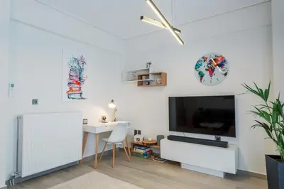 a white living room with a tv and a table at Bright 2 Bedroom Apartment Helios by Philoxenia in Athens
