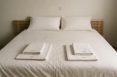 a white bed with two folded towels on it at Apartment for 4 with Acropolis view - Athens 5km Piraeus 5km Metro 5' walk in Piraeus