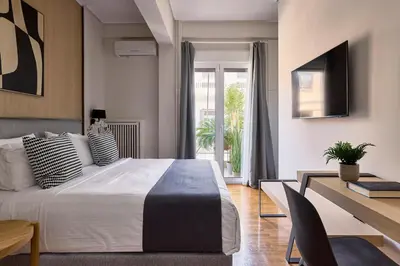 a bedroom with a bed and a desk and a television at Acropolis Delight Residence II in Athens