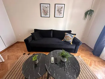 a living room with a black couch and a glass table at Check Point - Acropolis Shadow in Athens
