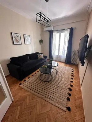 a living room with a black couch and a table at Check Point - Acropolis Shadow in Athens