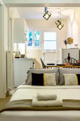 a bedroom with a large white bed and a kitchen at Galini Acropolis Lux Apartment in Athens