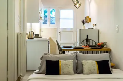 a room with a bed with pillows and a kitchen at Galini Acropolis Lux Apartment in Athens