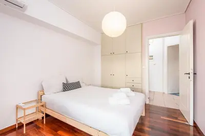 a white bedroom with a white bed and a mirror at Cozy appartment in Neo Faliro, Piraeus in Piraeus