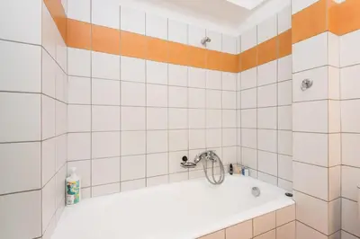 a white tiled bathroom with a bath tub at Cozy appartment in Neo Faliro, Piraeus in Piraeus