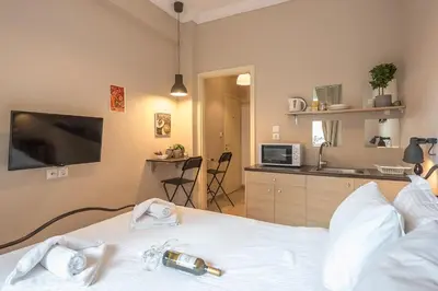 a bedroom with a bed with a tv and a kitchen at Elegant Hermes Suite in Athens, by Acropolin in Athens