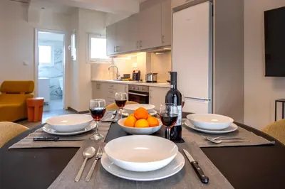 a table with a bowl of oranges and glasses of wine at Modern 1BR - 19min to Center, Fiber Internet in Athens