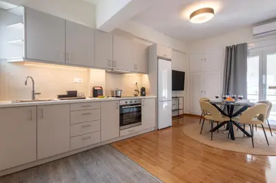 a kitchen with white cabinets and a table with chairs at Modern 1BR - 19min to Center, Fiber Internet in Athens