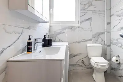 a white bathroom with a sink and a toilet at Modern 1BR - 19min to Center, Fiber Internet in Athens