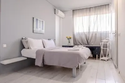 a white bedroom with a bed and a window at Windows with view in Athens