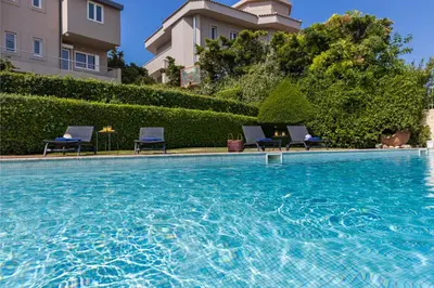 a swimming pool with chairs in front of a building at Blue Horizon Villa in Kalívia Thorikoú