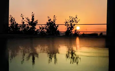 a sunset over a pool of water with trees at The ROSE Luxury Penthouse with Private Swimming Pool in Athens