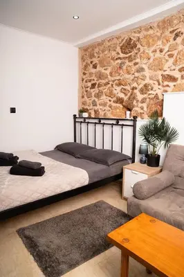 a bedroom with two beds and a stone wall at Tsigros Apartments B in Athens