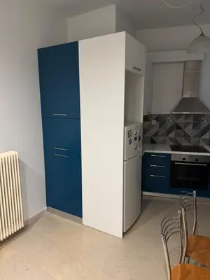a kitchen with blue cabinets and a white refrigerator at Tataoulon 22, Nea Smirni in Athens