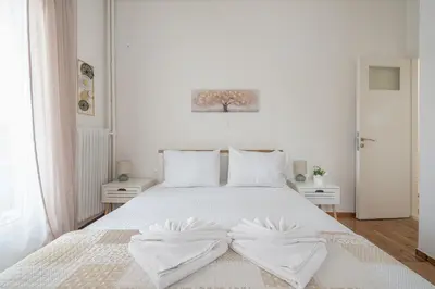 a white bedroom with a white bed with two towels on it at Ble Elia Thiseio Suite in Athens