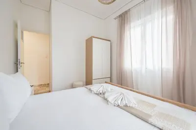 a bedroom with a white bed with a large window at Ble Elia Thiseio Suite in Athens
