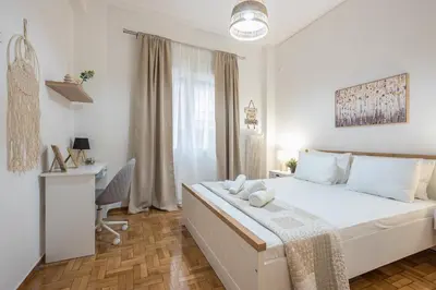 a white bedroom with a bed and a desk at Ble Elia Thiseio Suite in Athens