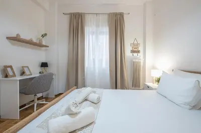 a white bedroom with a white bed and a desk at Ble Elia Thiseio Suite in Athens