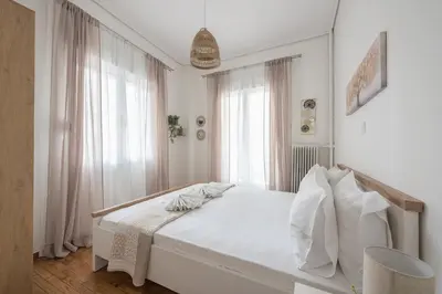 a white bedroom with a bed and a window at Ble Elia Thiseio Suite in Athens
