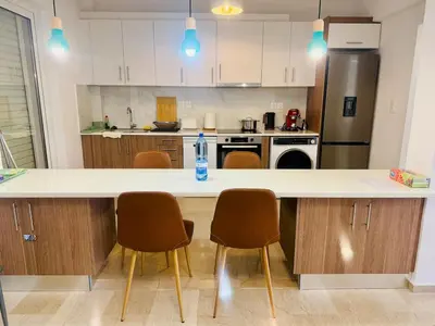 a kitchen with a counter with chairs and a refrigerator at \u96c5\u5178\u5357\u90e8\u6d77\u6ee82km\u7684\u8212\u9002\u5bbd\u655e\u516c\u5bd3 in Athens